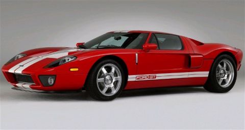 1990 Ford Bronco - Red Ford GT sports car with white racing stripes, seen from a three-quarter front angle. The 'FORD GT' designation is visible on the side.