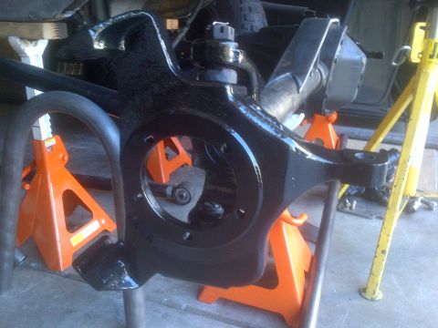 1985 Jeep CJ7 - A black suspension component is supported by orange jack stands in a garage setting.