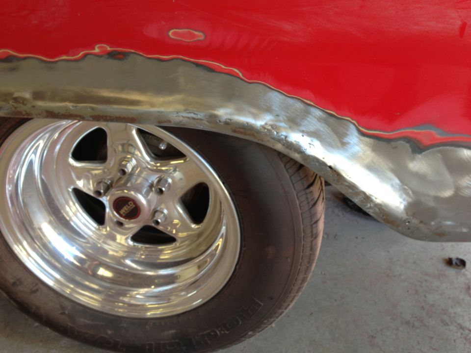 Close-up of a car's rear fender and a Weld racing wheel. The fender shows metalwork and primer