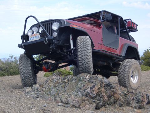1985 Jeep CJ7 - This modified Jeep is navigating a rocky trail, its off-road capabilities.