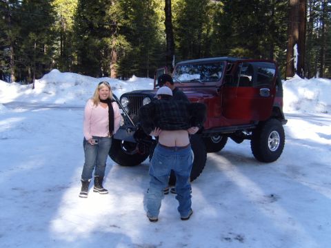 1985 Jeep CJ7 - A red 1985 Jeep CJ7 is parked in a snowy wooded area with two people.