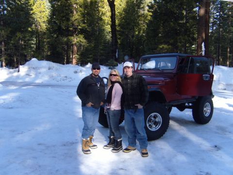 1985 Jeep CJ7 - A group poses with a red Jeep CJ in a snow-covered forest.