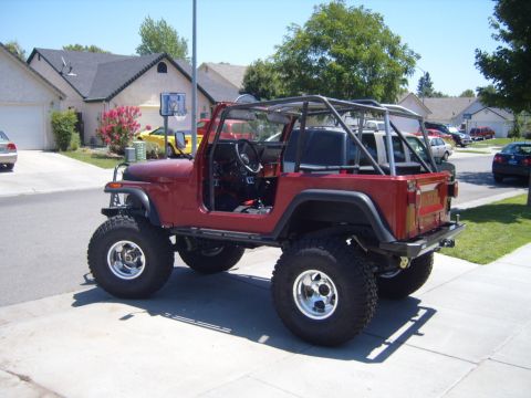 1985 Jeep CJ7 - This red 1985 Jeep CJ7 features a roll cage and is lifted with oversized tires.