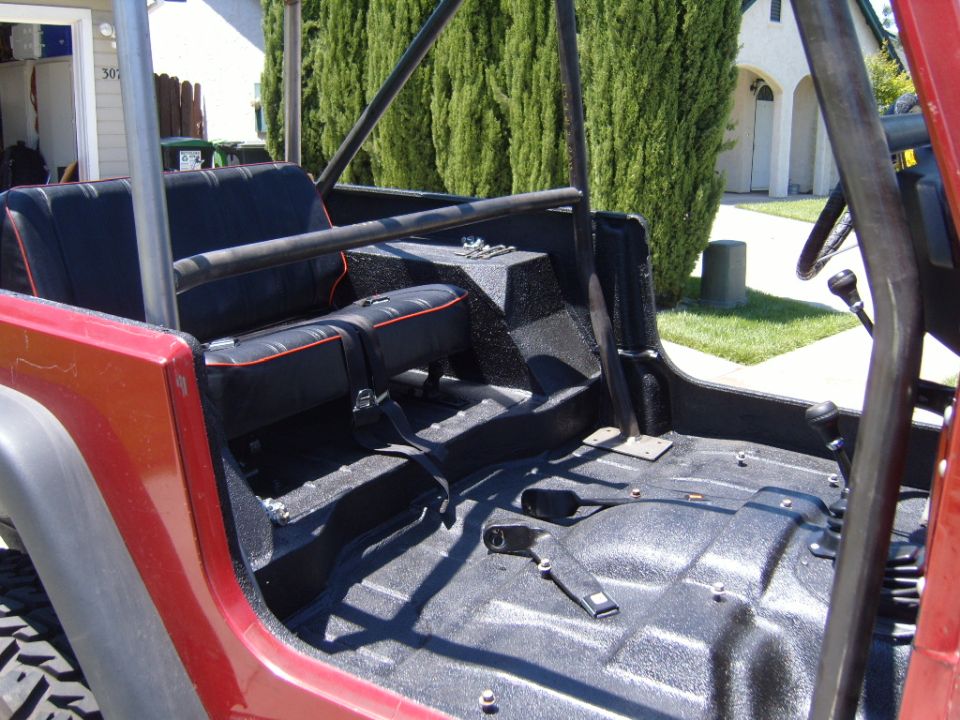 Red Jeep CJ interior with black seats and roll cage. Floor is black textured