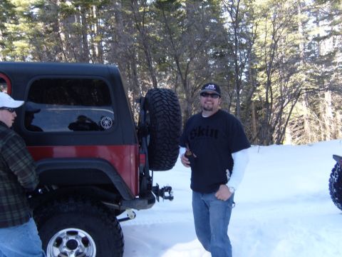 1985 Jeep CJ7 - A man stands next to a red Jeep CJ7 in a snowy, wooded area.
