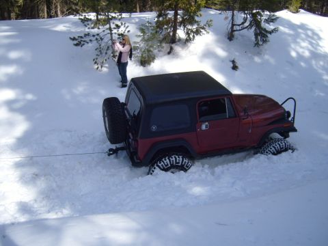 1985 Jeep CJ7 - A red Jeep is partially buried in snow, with a person observing the scene.