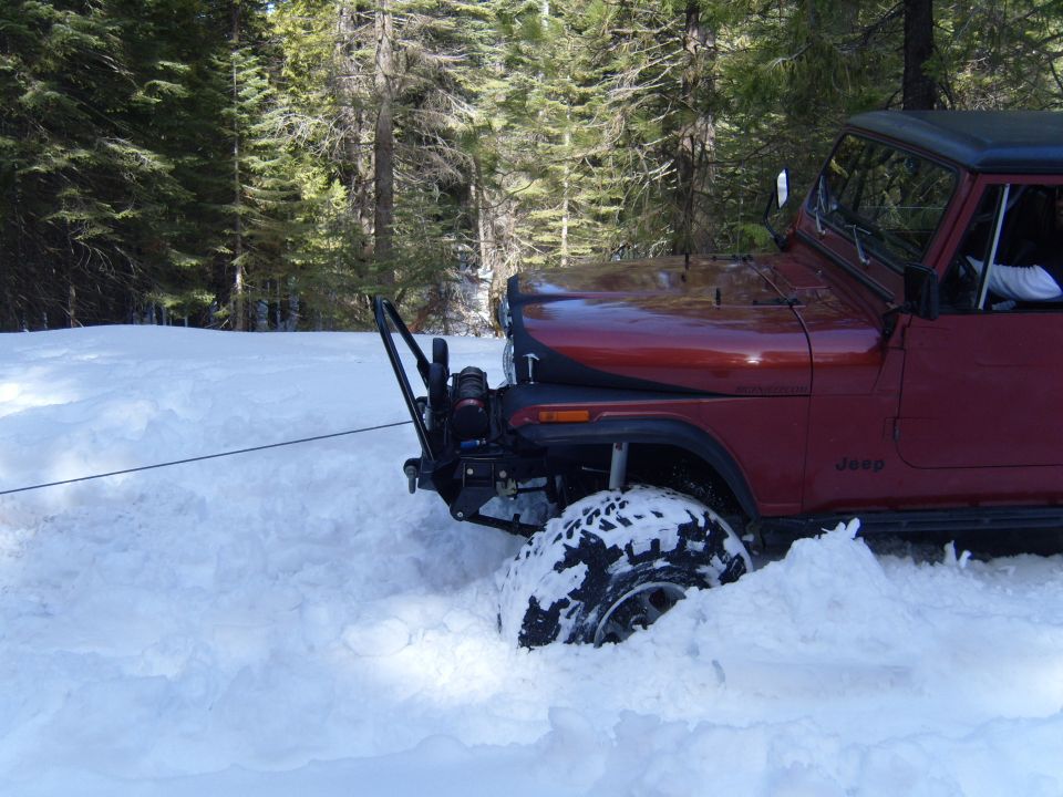 Red Jeep stuck in deep snow, winch cable attached to front bumper