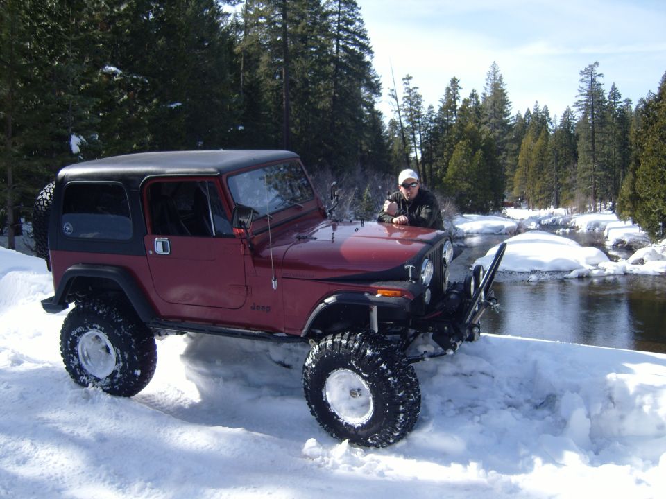 Maroon Jeep CJ7 with a black hardtop in snow, front-left quarter view