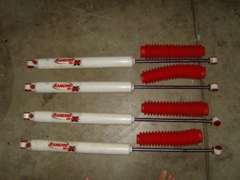 1985 Jeep CJ7 - Four Rancho RS9000 shock absorbers are displayed on a concrete floor, each red bellows.