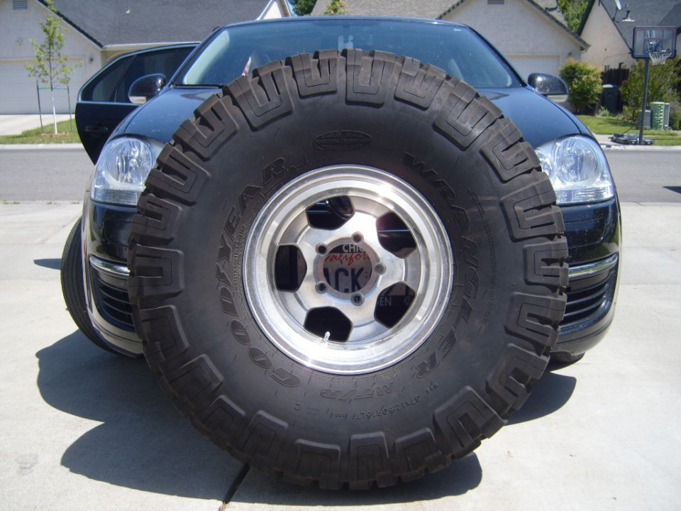 Spare tire obscuring the front of a black car. The tire has 'GOODYEAR' visible