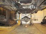 1985 Jeep CJ7 - The underside of a vehicle is shown, supported by jack stands, with focus on the suspension and drivetrain.