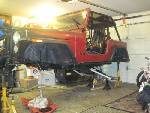 1985 Jeep CJ7 - Jeep CJ body is elevated on jack stands inside a garage, undergoing some work.