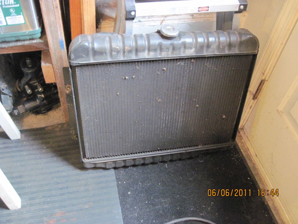 Automotive radiator with a metal cap on top, sitting on a dark mat