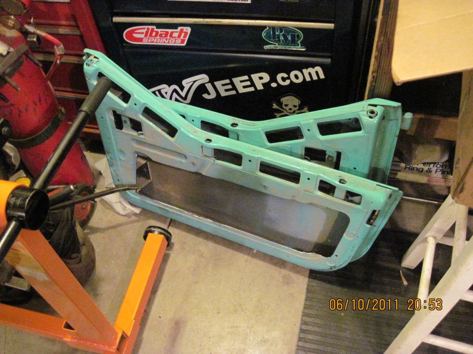 Two teal Jeep doors disassembled and resting on a stand