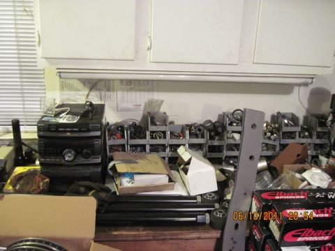 1985 Jeep CJ7 - A workbench is cluttered with various automotive parts, a stereo system, and storage bins.