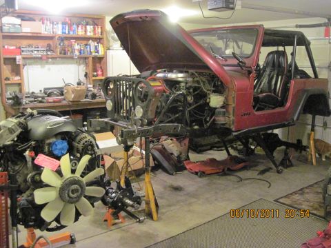 1985 Jeep CJ7 - Jeep CJ7 undergoing repairs in a workshop, with engine and parts disassembled.