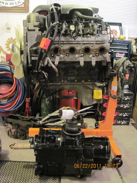 1985 Jeep CJ7 - Engine and transmission assembly displayed on an orange engine stand in a workshop setting.