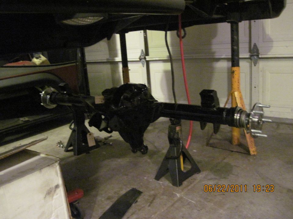 rear axle assembly on jack stands in garage, part of a vehicle is visible above