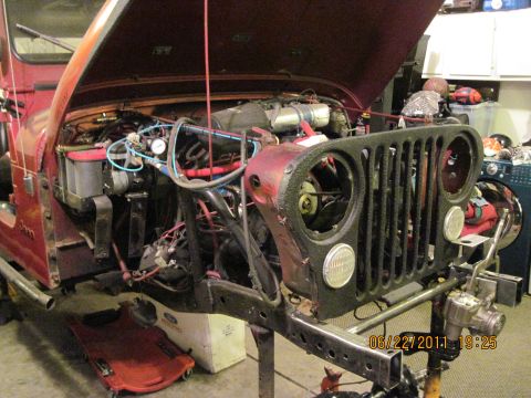 1985 Jeep CJ7 - Front end of a 1985 Jeep CJ7 disassembled for engine work, showing the engine bay and grille area.
