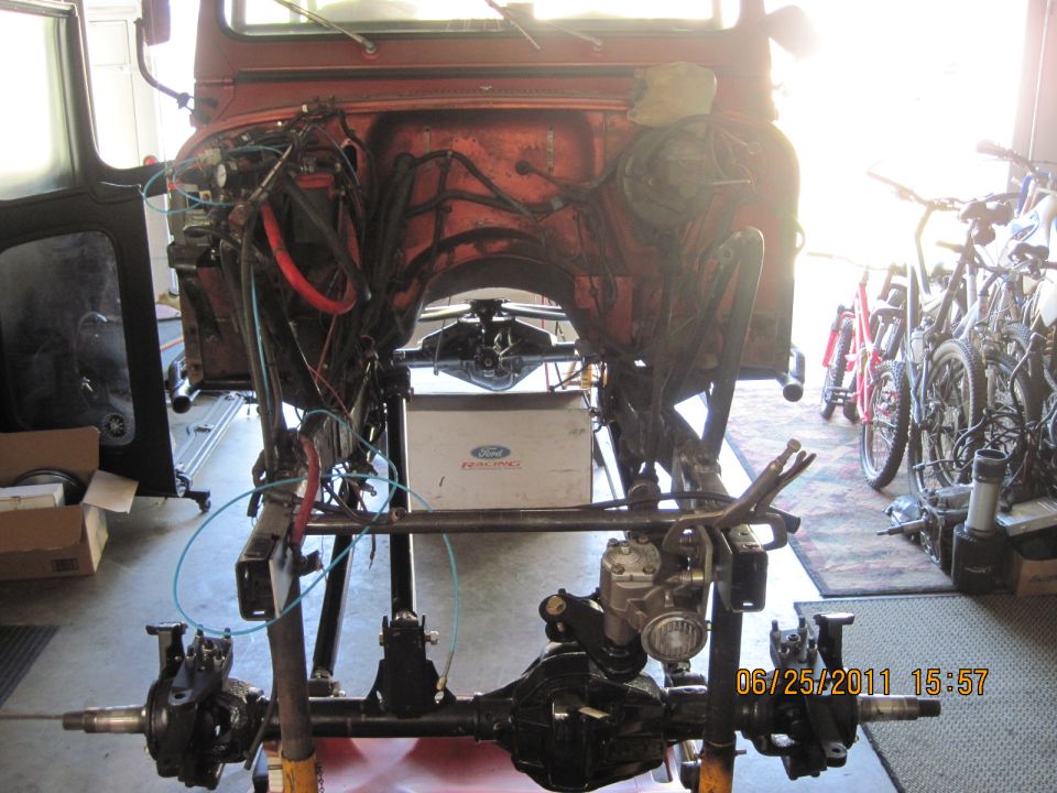 orange vehicle body on stand, front axle and drivetrain exposed, Ford fuel tank visible