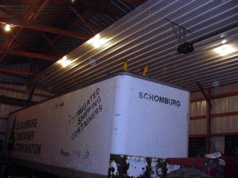 1992 Ford Bronco - A white corrugated shipping container is stored inside a barn, with visible text identifying the owner and type of container.