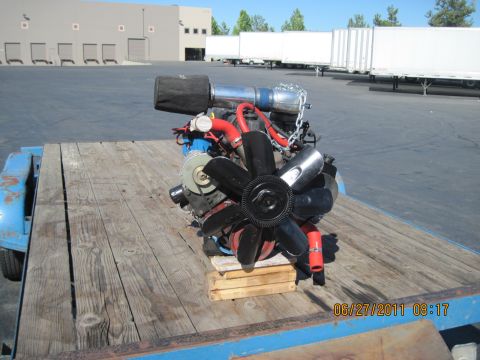 1985 Jeep CJ7 - Engine assembly with chrome intake and black fan sits on a wooden trailer.