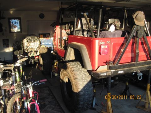1985 Jeep CJ7 - A red Jeep is shown in a garage with its rear end elevated on jack stands.