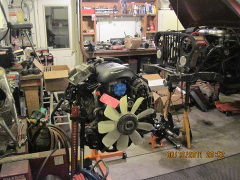 1985 Jeep CJ7 - A Jeep CJ-series grille and VORTEC engine are visible in a cluttered garage setting.