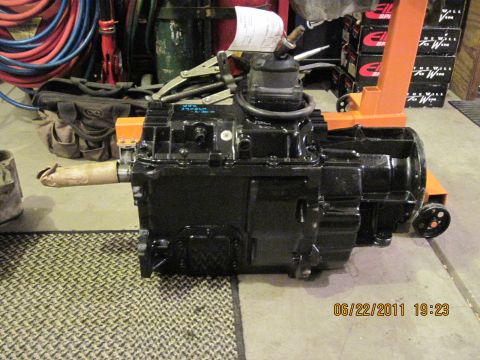 1985 Jeep CJ7 - Transmission unit shown on an engine stand, with workshop items in the background.