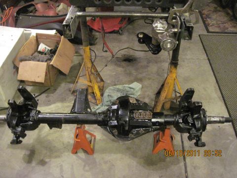 1985 Jeep CJ7 - A disassembled Jeep front axle assembly is supported by jack stands in a garage setting.