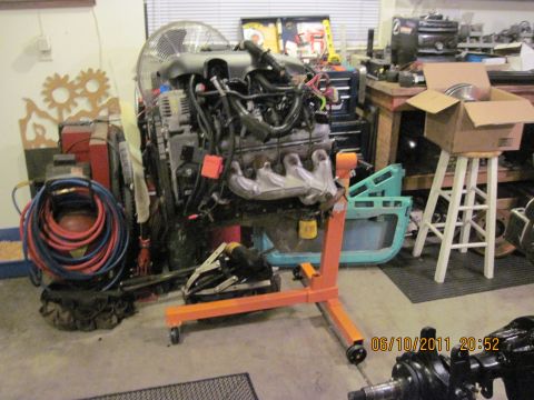 1985 Jeep CJ7 - An engine is mounted on a stand in a workshop, surrounded by various tools and equipment.