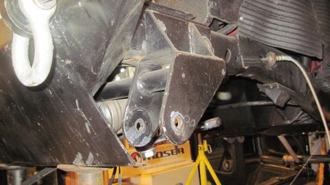 1985 Jeep CJ7 - Undercarriage view of vehicle suspension components, including brackets and a tow hook, with some text visible on a box below.