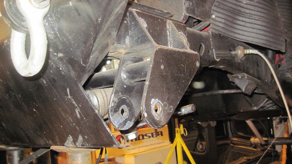 close-up of vehicle's undercarriage showing suspension brackets and a tow hook