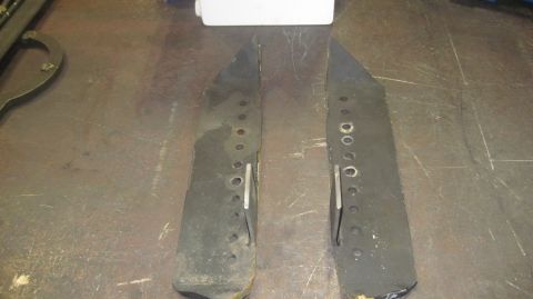 1985 Jeep CJ7 - Two black metal parts, possibly for a vehicle, are shown with multiple holes and metal tabs.