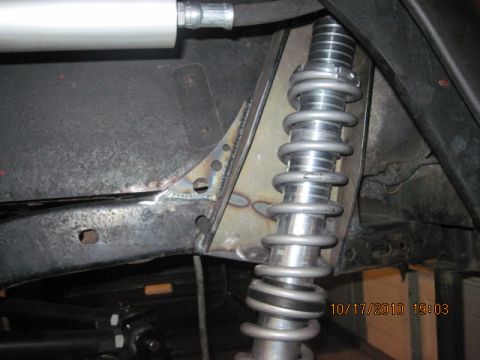 1985 Jeep CJ7 - Close-up view of a suspension coilover shock absorber and custom-welded bracketry on a vehicle frame.
