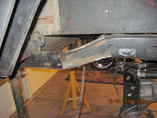 Vehicle frame section with suspension parts and a tire visible in the background
