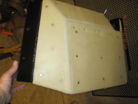 1985 Jeep CJ7 - A hand holds a cream-colored part with a black bracket, showing numerous screw holes.