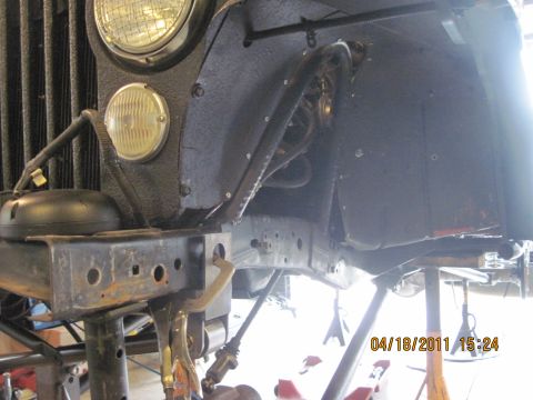 1985 Jeep CJ7 - Close-up view of the front wheel well and chassis of a Jeep, showing suspension components and frame structure.