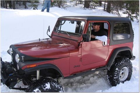 1985 Jeep CJ7 - Driver in a red 1985 Jeep CJ7 navigates snowy terrain.