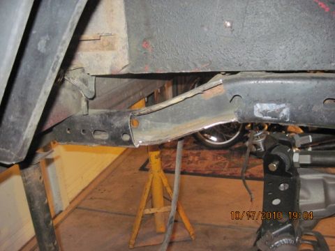 1985 Jeep CJ7 - Close-up view of a vehicle's frame undergoing modification, supported by yellow jack stands.