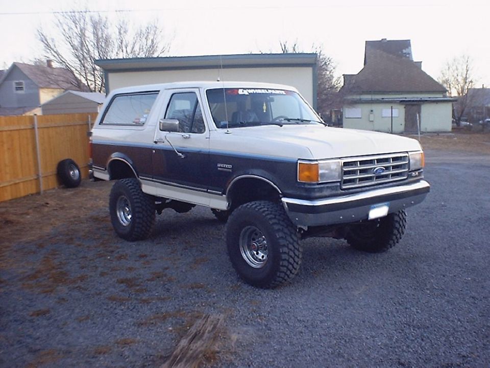 White and dark two-tone lifted Ford Bronco on large off-road tires, front 3/4 view