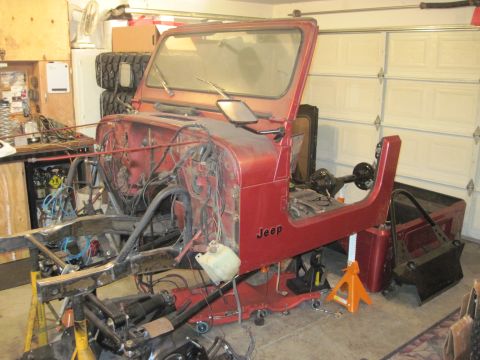 1985 Jeep CJ7 - Disassembled red Jeep CJ in a garage, with "Jeep" badging visible on the side panel.