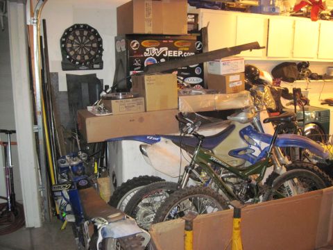 1985 Jeep CJ7 - A collection of motorcycles and various items are packed into a garage space.