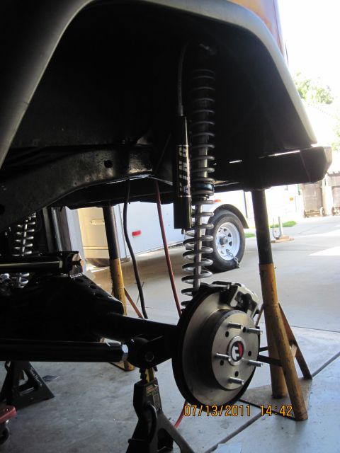 1985 Jeep CJ7 - Jeep suspension and brake components are visible while the vehicle is elevated on jack stands.