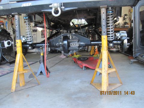 1985 Jeep CJ7 - Underside view of a Jeep being worked on, with the rear axle and suspension clearly visible.
