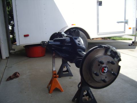 1985 Jeep CJ7 - A disassembled Jeep rear axle assembly is shown on jack stands, with a white trailer in the background.