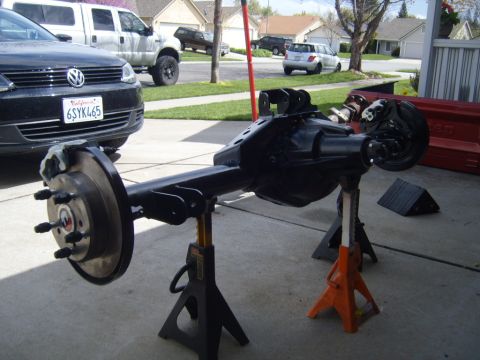1985 Jeep CJ7 - Rear axle assembly on jack stands, with other vehicles and houses in the background.