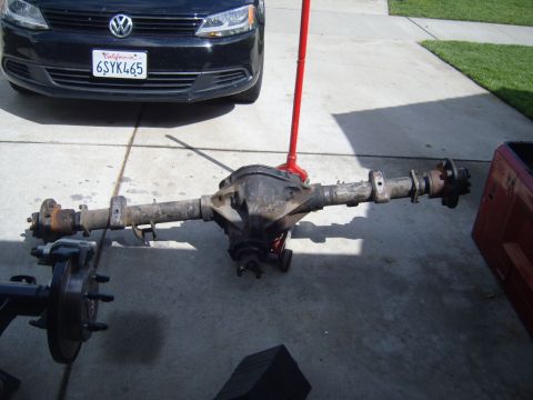 1985 Jeep CJ7 - A rear axle assembly is shown on a concrete surface, with the front of a black Volkswagen Jetta visible behind it.