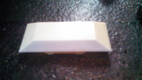 1979 Ford Bronco - A white plastic trim piece is shown on a dark, speckled surface.