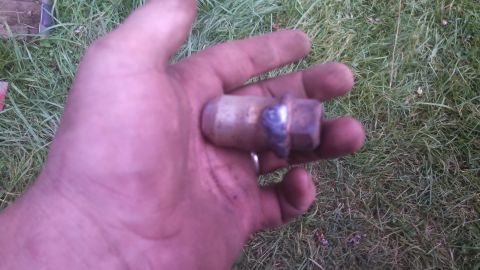 1979 Ford Bronco - A lug nut is held in a hand over grass.